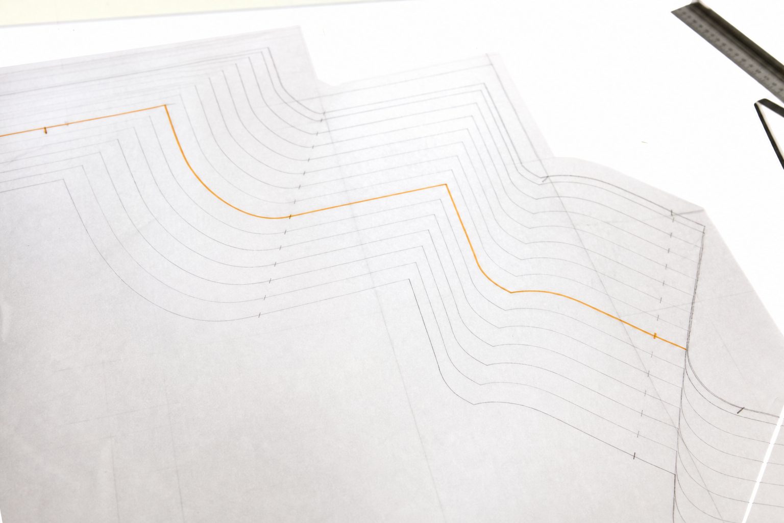 Nested pattern grading lines on translucent paper lit from below on a light table